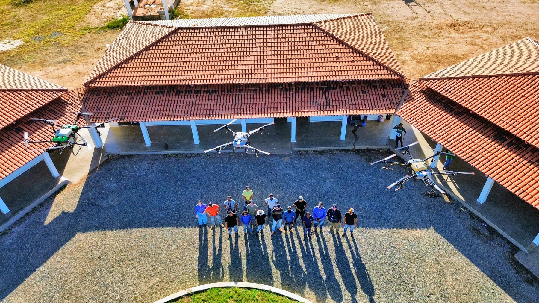 Vista aérea de uma área com edificações, equipe e drones, enviada pela Flygraph